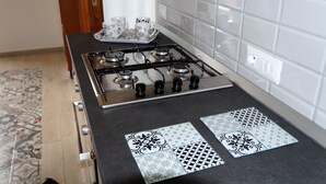 A kitchen with a gas stove, a tray with cups, and patterned tiles on the countertop. - Nolana 86 (Pompei)