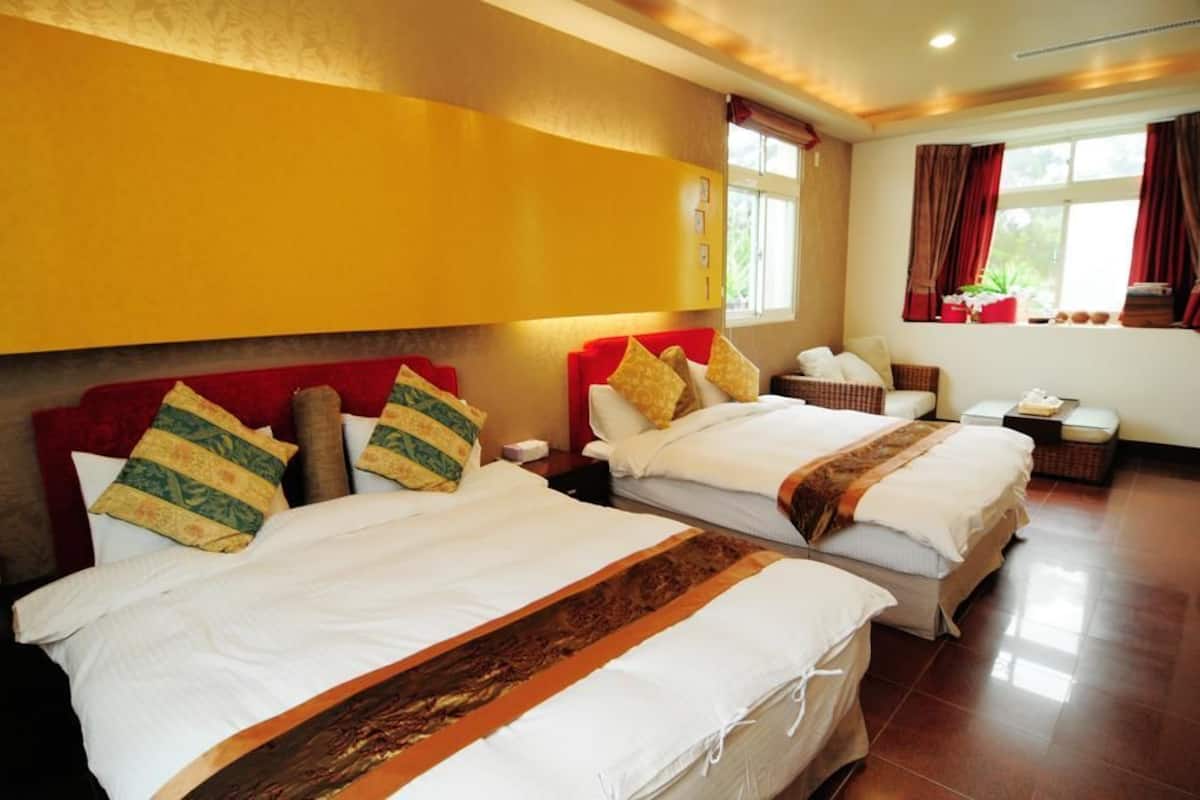 A hotel room with two beds, a red headboard, and a window with curtains.