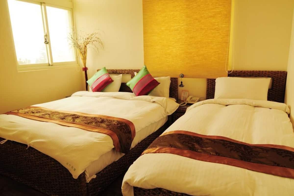 A hotel room with two beds, a window, and a wall-mounted telephone.