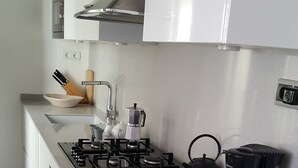 A modern kitchen with a gas stove, kettle, coffee maker, and a range hood. - The Sky penthouse in the center of town with panoramic views and sunny terrace (Sitges)
