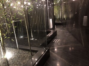 A modern bathroom with a glass enclosure, a bamboo plant, and a marble floor. - Birdman Motel (Taichung)
