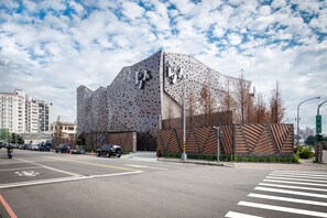 A modern building with a unique perforated facade and a large entrance gate. - Birdman Motel (Taichung)