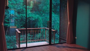 Een kamer met een groot raam met uitzicht op een weelderige groene tuin.