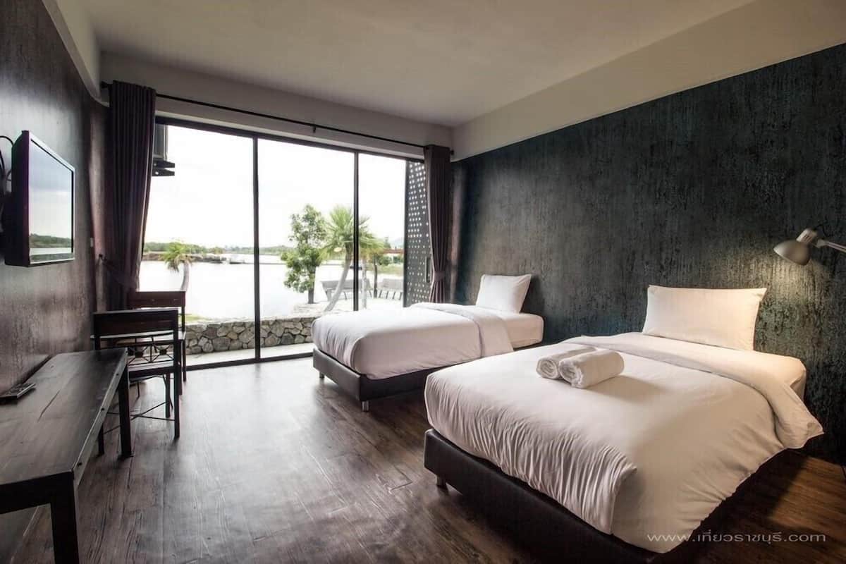 A hotel room with two beds, a desk, and a large window offering a view of the outdoors.