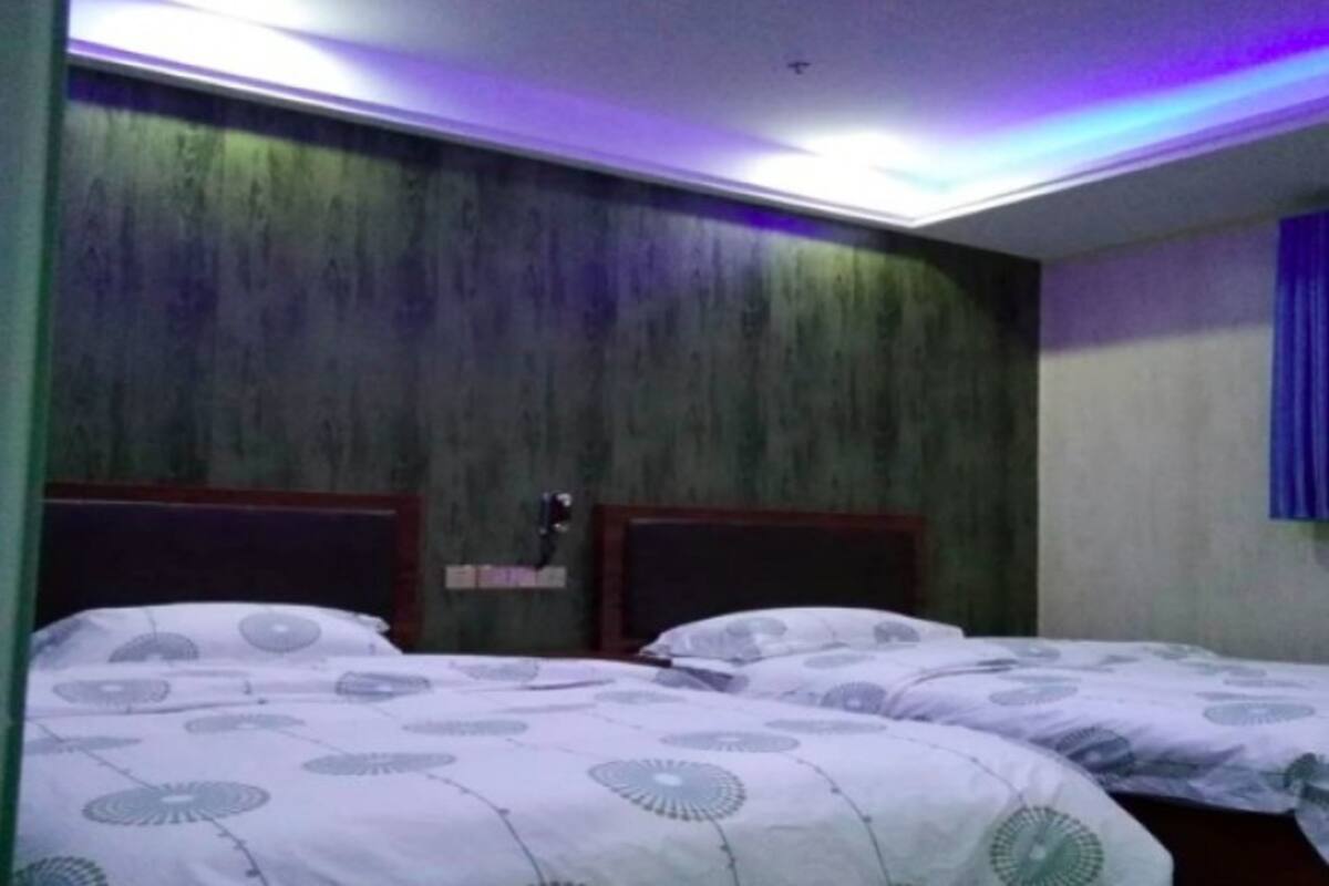 Una habitación con dos camas, cada una con una colcha estampada. La habitación tiene un cabecero de madera y un techo con una lámpara.