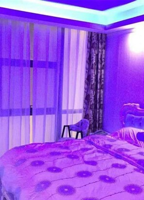 Une chambre à coucher avec un lit, une chaise et une fenêtre avec des rideaux.