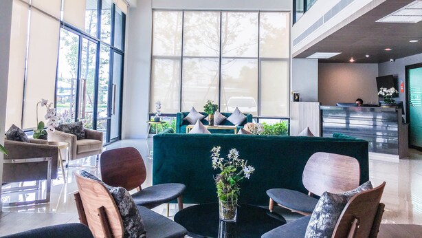 A spacious lobby with a reception desk, seating area, and large windows offering views of the outdoors. - Fortune Hotel Buriram (Buriram)