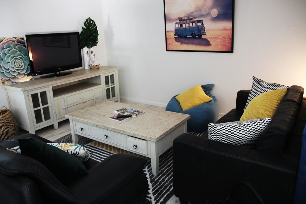 A living room with a television, a coffee table, a sofa, and a painting on the wall.