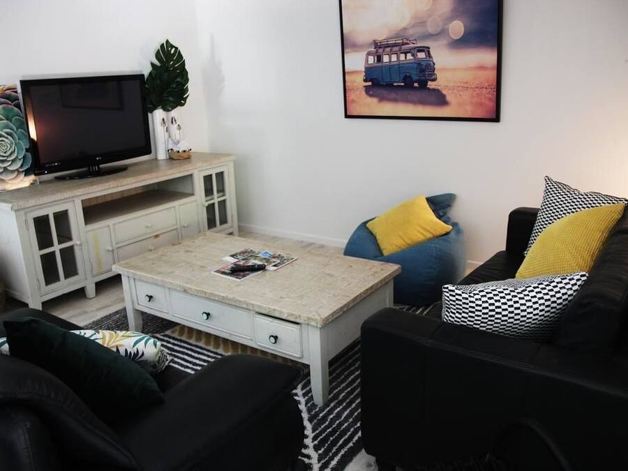 A living room with a television, a coffee table, a sofa, and a painting on the wall.