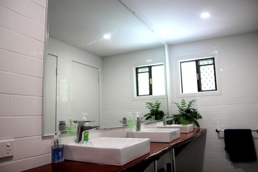 A modern bathroom with two sinks, a large mirror, and a window.