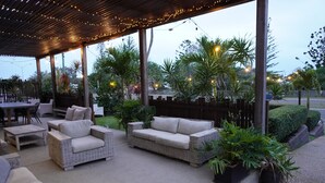 An outdoor patio area with wicker furniture, string lights, and potted plants. - Yeppoon Beachhouse - Hostel (Yeppoon)