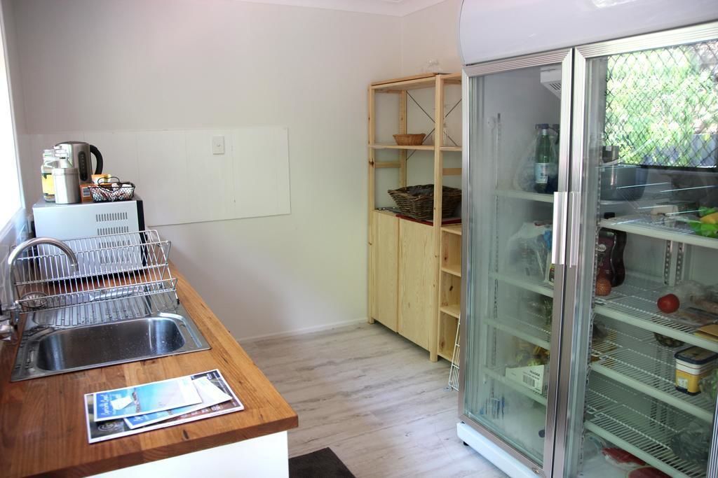 A kitchen with a stainless steel sink, wooden countertop, and a glass-fronted refrigerator.