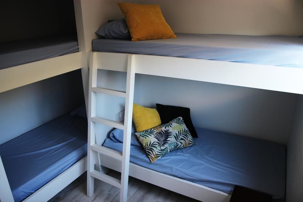 A bunk bed with a ladder, blue bedding, and multiple pillows.
