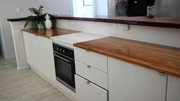 Eine Küche mit weißen Schränken, einer Holzausziehtafel und einem eingebauten Backofen.
