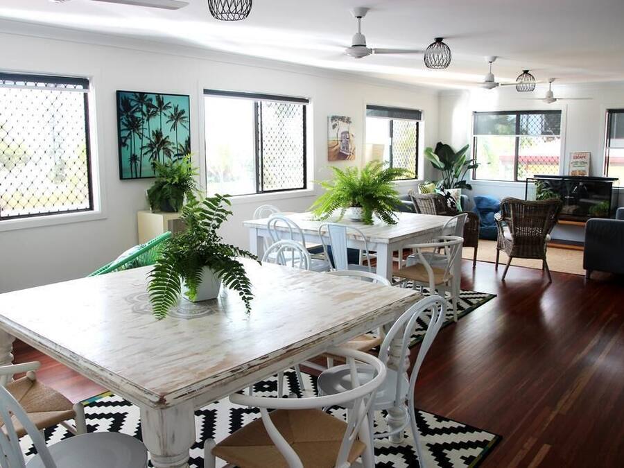 A dining area with a white table and chairs, surrounded by potted plants and artwork.