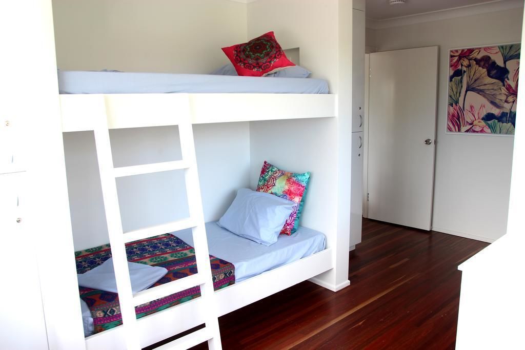 A bunk bed with a ladder, a door, and a painting on the wall.