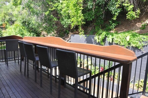 A wooden deck with outdoor furniture and a railing. - Yeppoon Beachhouse - Hostel (Yeppoon)