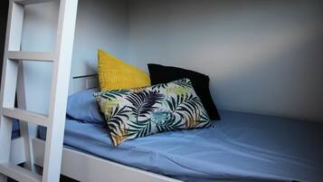 A bunk bed with a blue mattress and two pillows, one yellow and one with a leaf pattern.