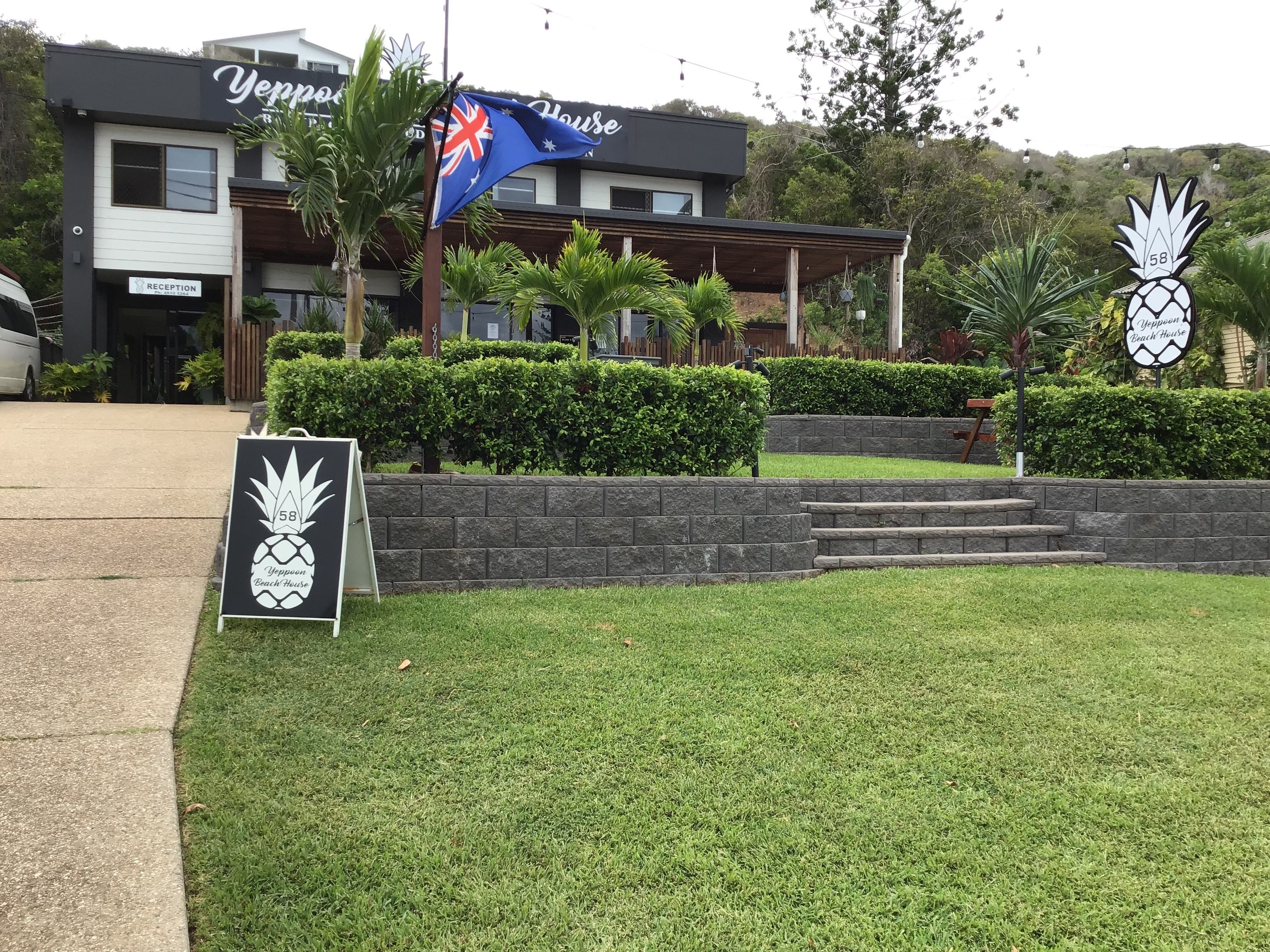 Un área de recepción con un cartel que dice 'Yempow Beach House' y una bandera.
