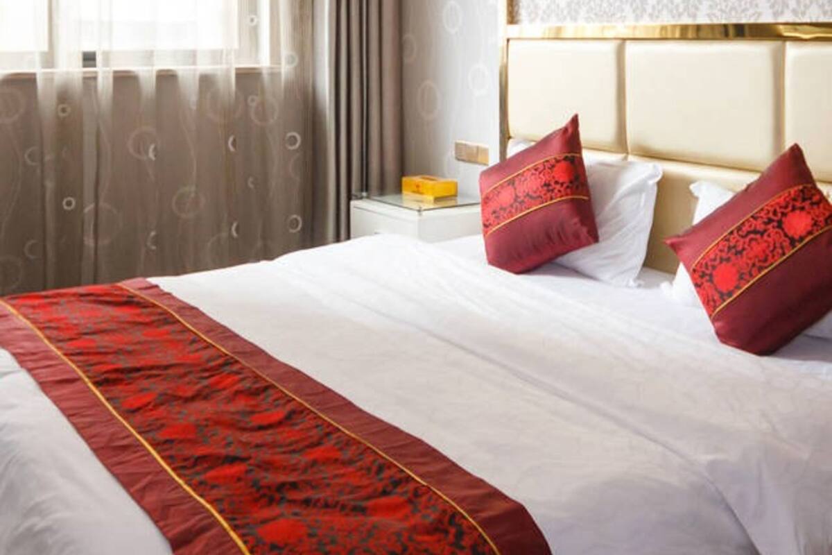 Quarto de hotel com uma cama grande, uma mesa de cabeceira e um objeto decorativo na parede.