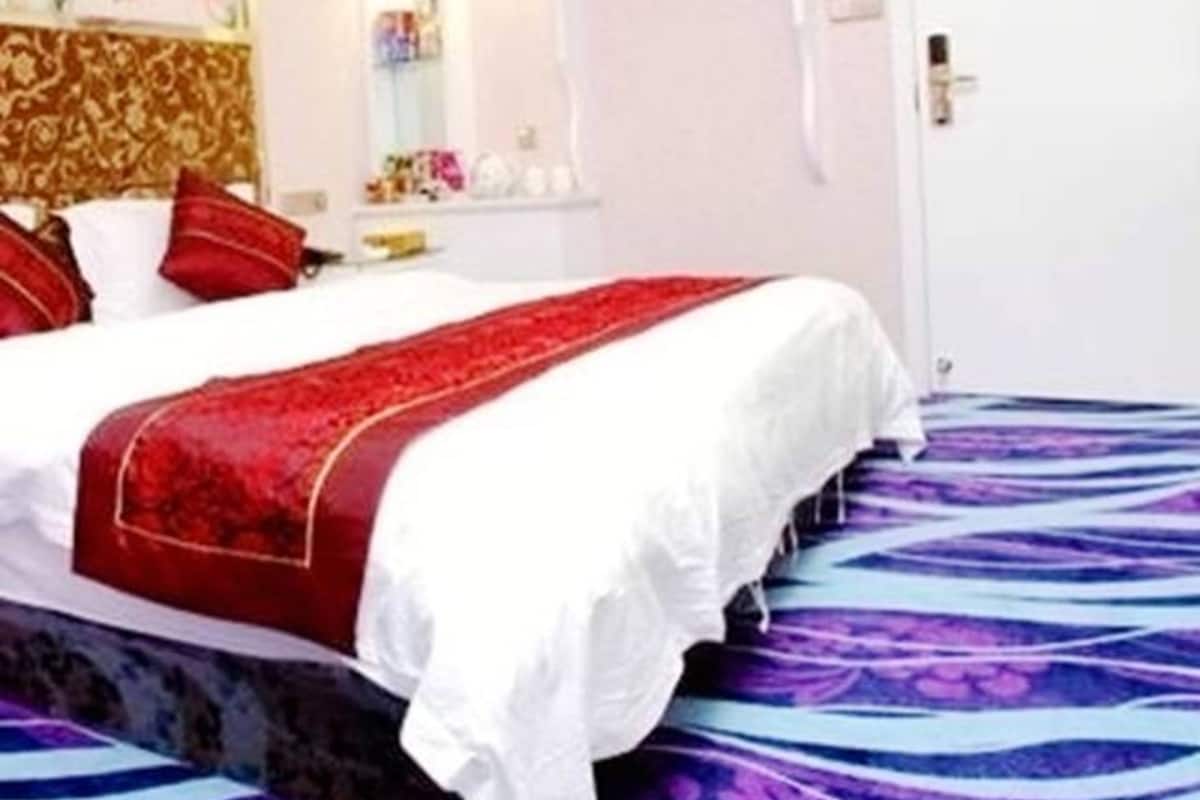 Quarto de hotel com uma cama grande, uma mesa de cabeceira, um espelho e uma porta.
