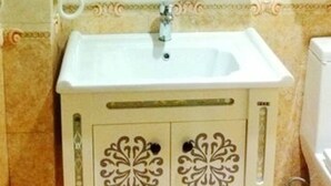 Un bagno con un lavandino bianco, uno specchio e un porta asciugamani.