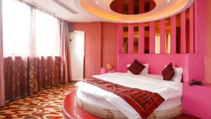 Camera d'albergo con un letto grande, una lampada a soffitto circolare e vista all'esterno attraverso la finestra.
