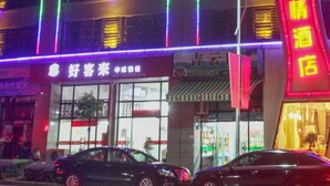 Un edificio illuminato da luci LED colorate, con un cartello che indica un hotel e auto parcheggiate.