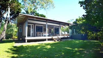 A modern house with large windows, a covered porch, and a well-maintained lawn.