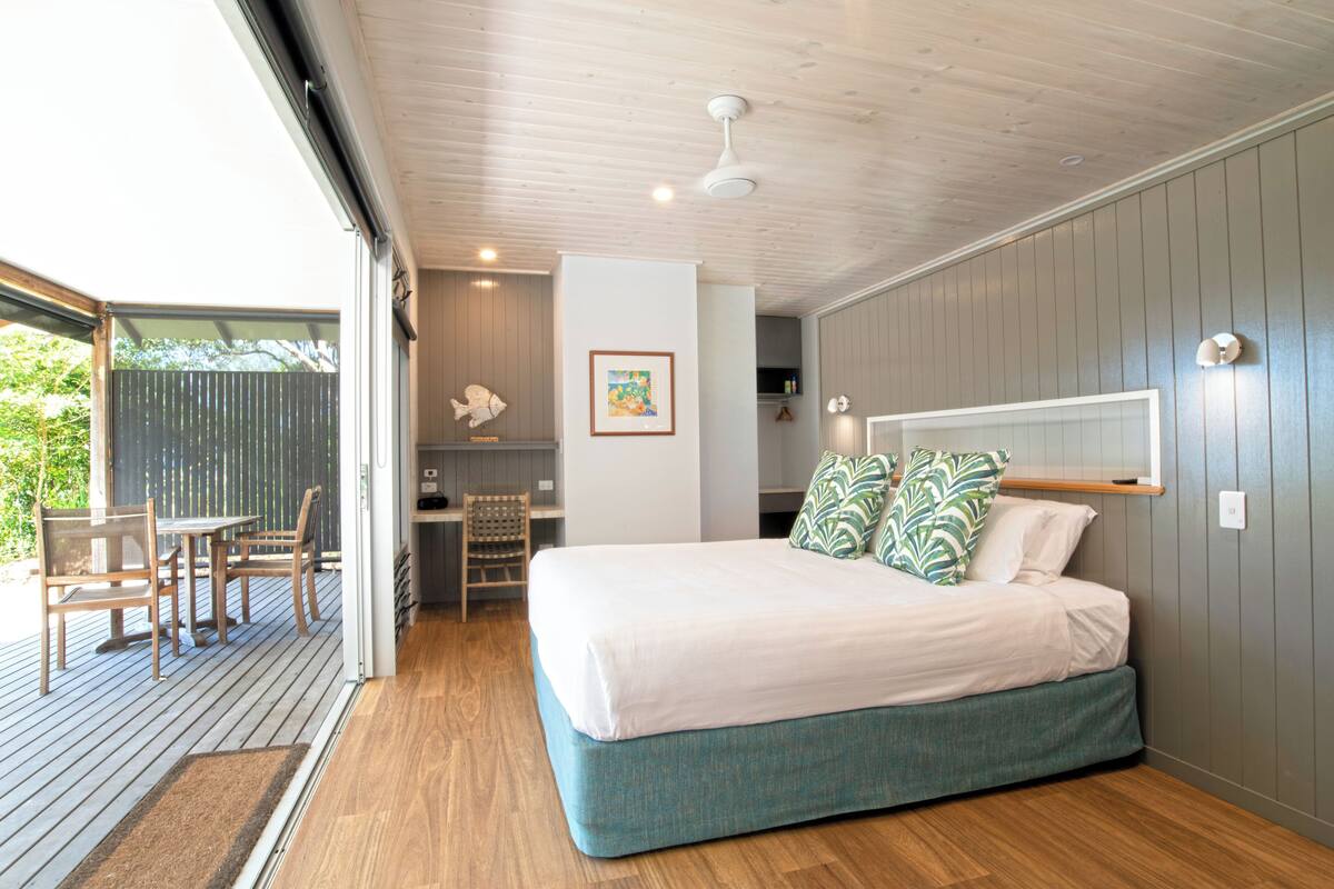 A bedroom with a bed, a desk, and a chair.