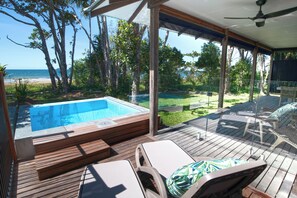 A poolside area with a hot tub, lounge chairs, and a view of the beach. - The Bungalows (Wongaling Beach)