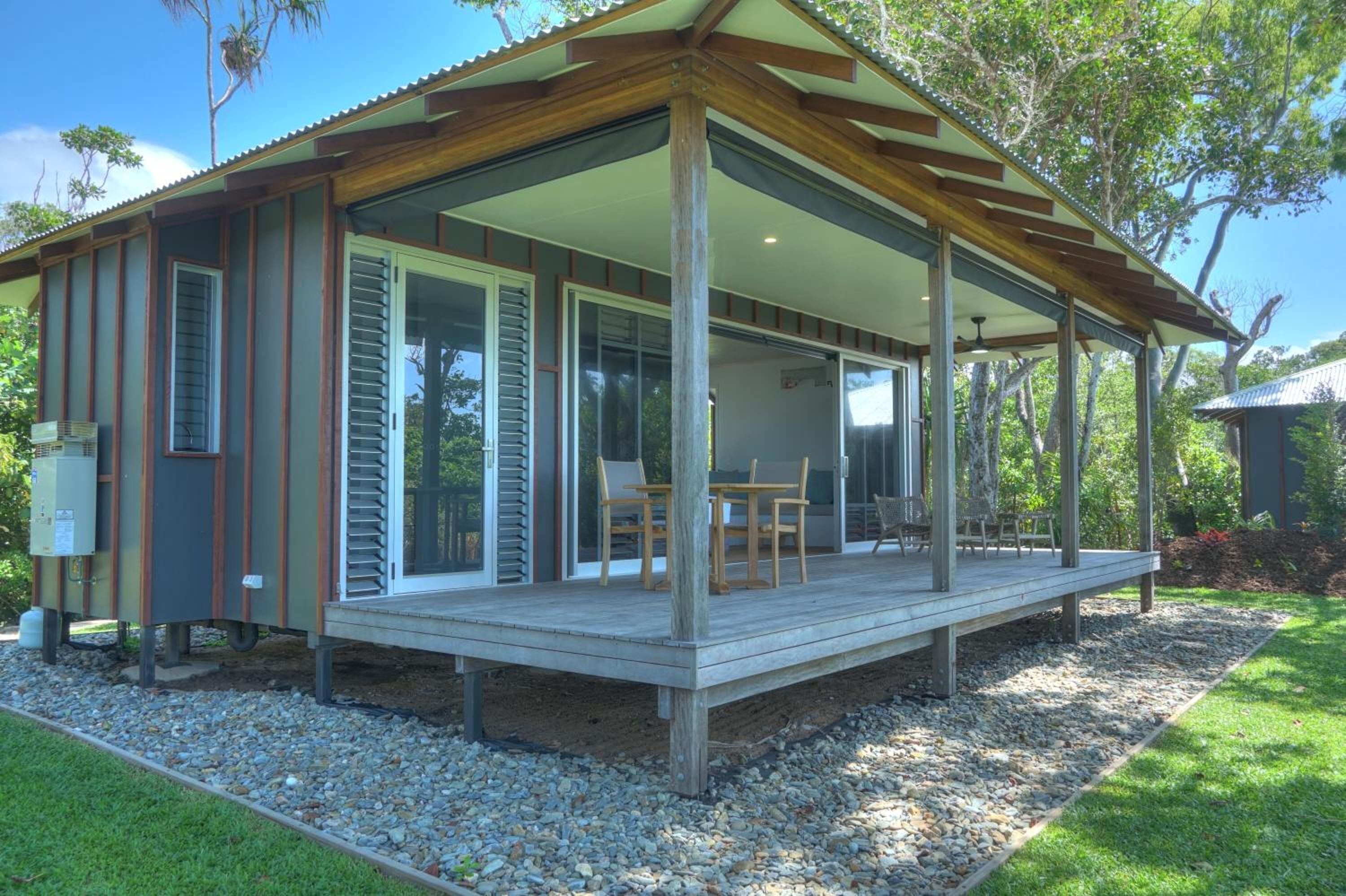 A modern house with a covered porch, large sliding glass doors, and a wooden deck.