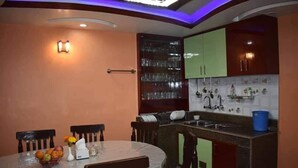 A kitchen with a round dining table, chairs, a glass cabinet, and a built-in sink. - Golden heaven homestay (Kathmandu)