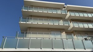 Un edifici de diversos pisos amb balcons i un cel blau clar.