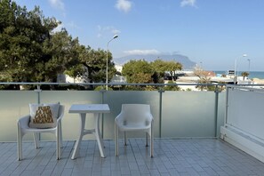 A balcony with two white chairs, a small table, and a view of the sea and distant mountains. - M146 - Marcelli, bilocale fronte mare con ampio terrazzo (Marcelli)