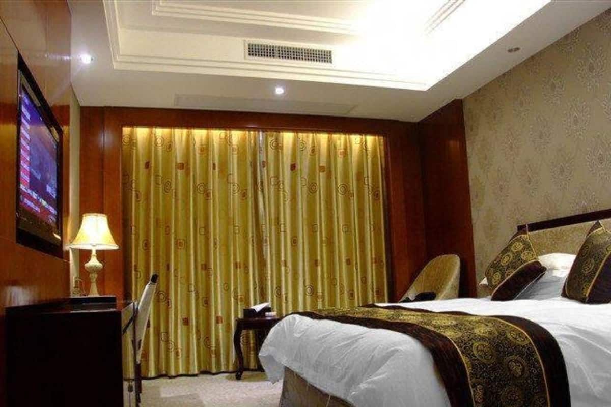 Une chambre d’hôtel avec un lit, une télévision, un bureau et un rideau.