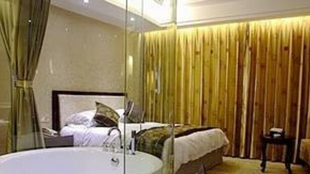 Habitació d'hotel moderna amb un llit gran, una taula de nit, un mirall i un mur revestit de fusta.