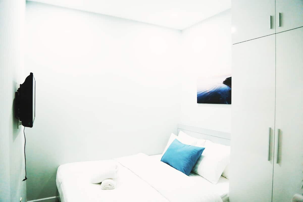 Une chambre d’hôtel avec un lit, une télévision et une armoire.