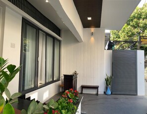 A modern building exterior with large windows, a bench, and potted plants. - Moonlight House & Apartment Nha Trang (Bac Nha Trang)