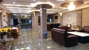 A hotel lobby with a reception desk, seating area, and a glass door entrance. - Xianfeng B&B (Hualien City)