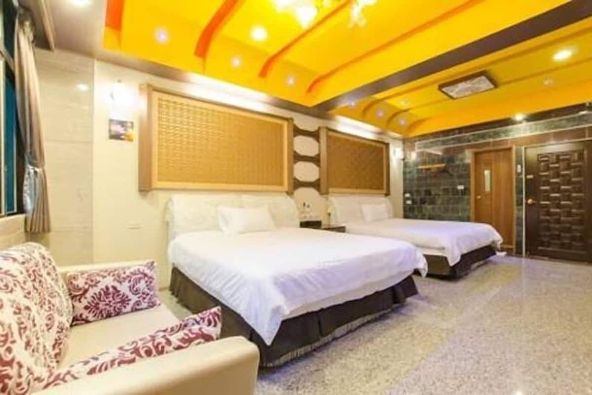 A hotel room with two beds, a sofa, and a decorative ceiling.
