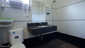 A bathroom with a white toilet, a black sink, and a shower. - Xianfeng B&B (Hualien City)