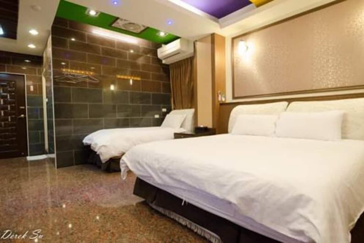 A hotel room with two beds, a stone wall, and a modern ceiling design.