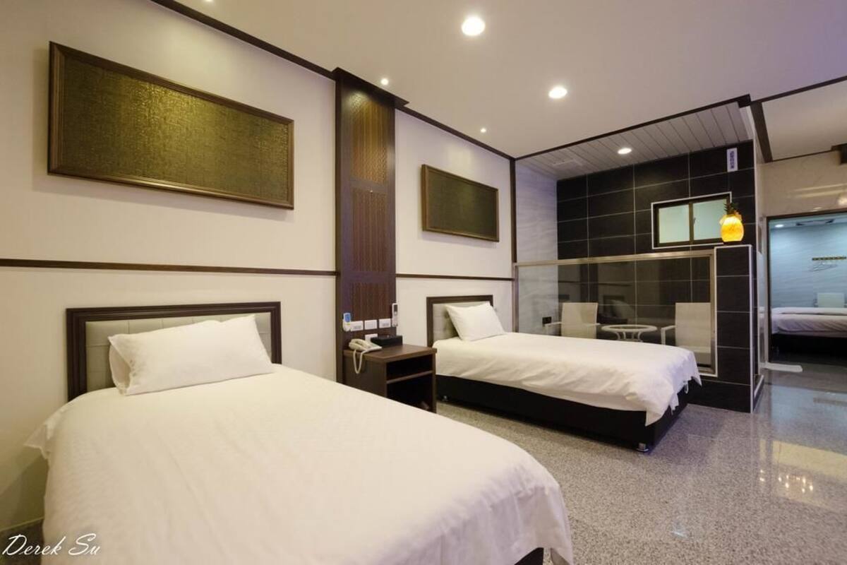 A hotel room with two beds, a minibar, a desk, and a large mirror.