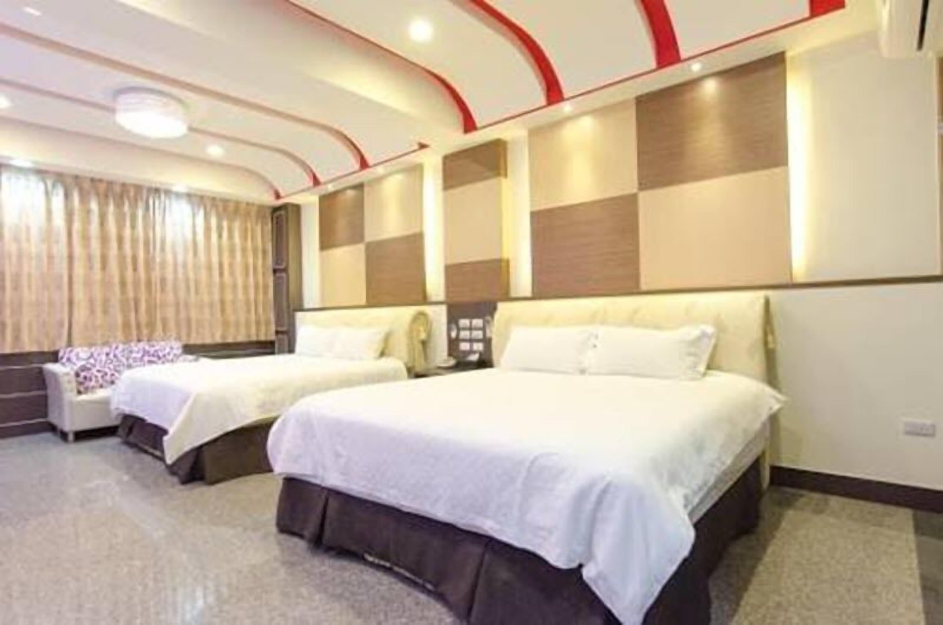 A hotel room with two beds, a sofa, and a large window with curtains.