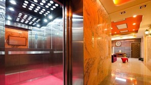 An elevator interior with a red carpet and a marble reception desk. - Xianfeng B&B (Hualien City)