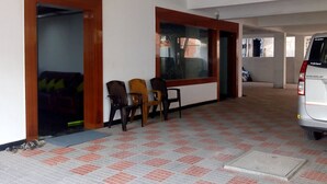 Amplio espacio interior con suelo de baldosas, varios ventanales de madera y un vehículo estacionado.