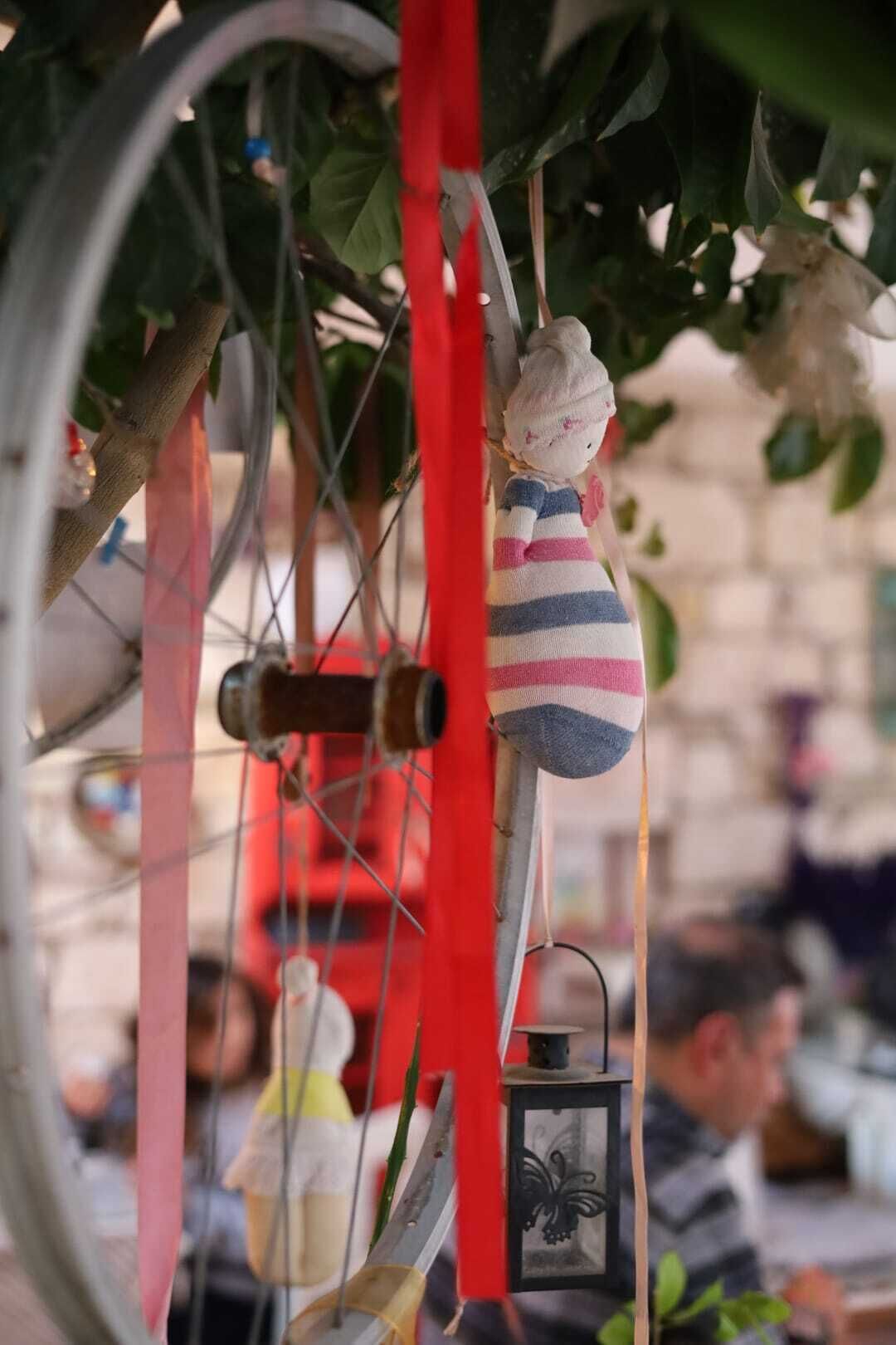 A bicycle with a small doll hanging from the handlebars and a lantern attached to the frame.