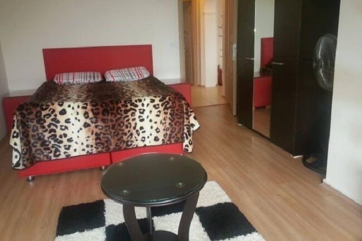 A bedroom with a bed, a small table, and a mirror.