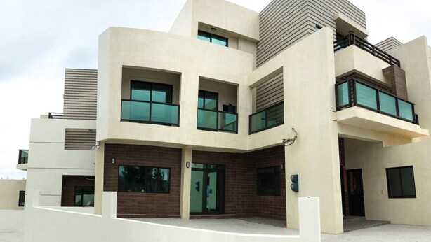 Un edificio moderno de varios pisos con techo plano, ventanas grandes y fachada de ladrillo y concreto.
